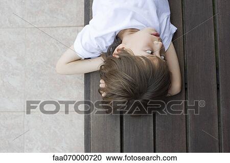 Boy lying on floor, looking away in thought View Large Photo Image Stock Image - Boy lying on floor, looking away in thought. Fotosearch