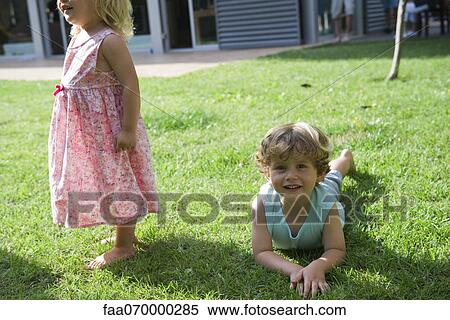 Boy playing on lawn with his sister View Large Photo Image Stock Photography - Boy playing on lawn with his sister. Fotosearch