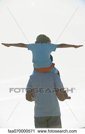 Boy riding on father's shoulders, rear view View Large Photo Image Stock Image - Boy riding on father's shoulders, rear view. Fotosearch