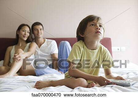 Boy watching TV in bed with his parents View Large Photo Image Stock Image - Boy watching TV in bed with his parents. Fotosearch