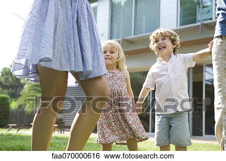 Stock Photograph - Children playing outdoors with their parents. Fotosearch