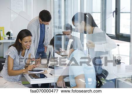 Stock Photo - Colleagues collaborating in office. Fotosearch