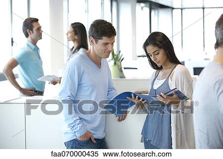 Colleagues looking over pamphlet together View Large Photo Image Stock Photography - Colleagues looking over pamphlet together. Fotosearch