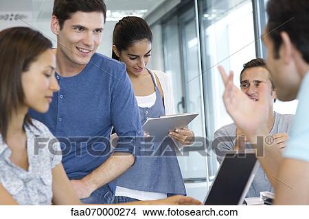 Picture - Colleagues talking together in office. Fotosearch