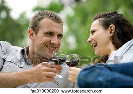Couple clinking wine glasses outdoors View Large Photo Image Stock Image - Couple clinking wine glasses outdoors. Fotosearch