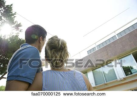 Couple contemplating exterior of house View Large Photo Image Stock Photography - Couple contemplating exterior of house. Fotosearch