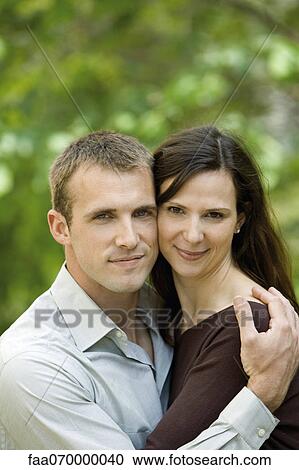 Stock Image - Couple embracing outdoors, portrait. Fotosearch