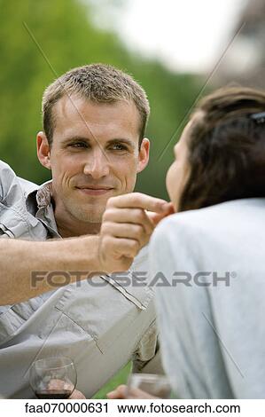 Couple enjoying romantic picnic, man feeding woman, cropped View Large Photo Image Stock Image - Couple enjoying romantic picnic, man feeding woman, cropped. Fotosearch