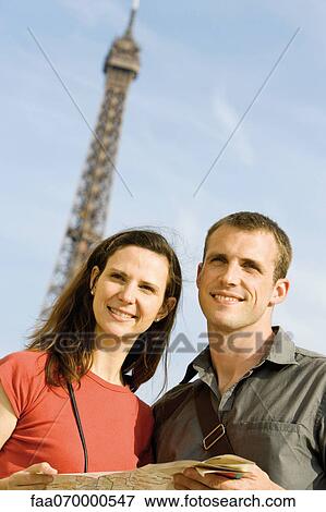 Couple holding map in front of Eiffel Tower, Paris, France View Large Photo Image Stock Photo - Couple holding map in front of Eiffel Tower, Paris, France. Fotosearch