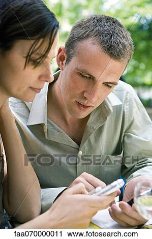 Couple outdoors, looking at cell phones View Large Photo Image Stock Image - Couple outdoors, looking at cell phones. Fotosearch