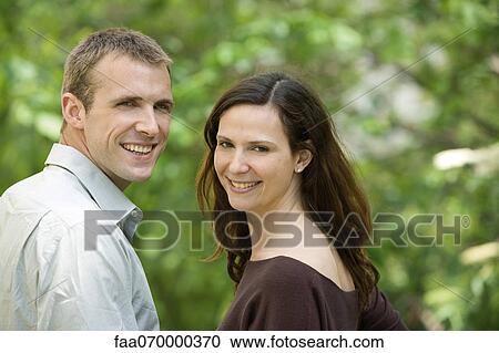 Stock Image - Couple smiling over shoulders at camera. Fotosearch