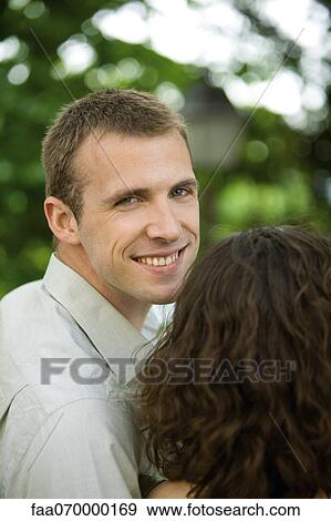 Couple together outdoors, man smiling over shoulder at camera View Large Photo Image Stock Photo - Couple together outdoors, man smiling over shoulder at camera. Fotosearch