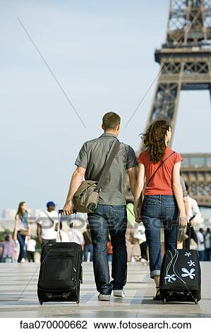 Couple walking with rolling luggage near Eiffel Tower, Paris, France View Large Photo Image Stock Image - Couple walking with rolling luggage near Eiffel Tower, Paris, France. Fotosearch