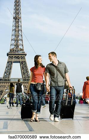 Couple walking with rolling luggage near Eiffel Tower, Paris, France View Large Photo Image Stock Photo - Couple walking with rolling luggage near Eiffel Tower, Paris, France. Fotosearch