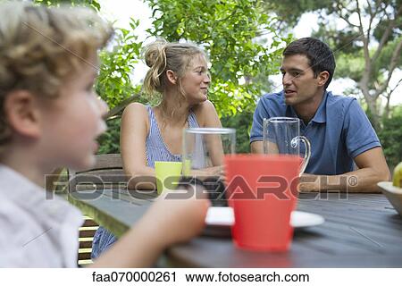 Family relaxing together at table outdoors View Large Photo Image Stock Image - Family relaxing together at table outdoors. Fotosearch