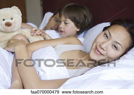 Family relaxing together in bed View Large Photo Image Stock Photo - Family relaxing together in bed. Fotosearch