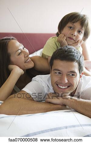 Stock Photo - Family relaxing together on bed. Fotosearch
