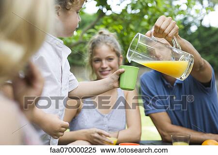 Family together outdoors, father pouring glass of juice for son View Large Photo Image Stock Photography - Family together outdoors, father pouring glass of juice for son. Fotosearch