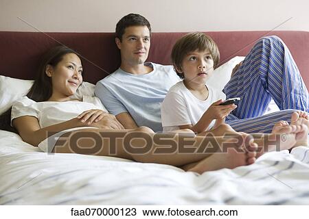Family watching TV in bed View Large Photo Image Stock Image - Family watching TV in bed. Fotosearch