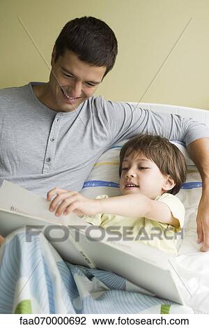 Father and son reading book together in bed View Large Photo Image Stock Image - Father and son reading book together in bed. Fotosearch