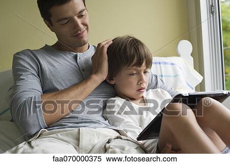 Father and son relaxing together with electronic book View Large Photo Image Stock Photography - Father and son relaxing together with electronic book. Fotosearch