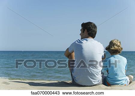 Father and son sitting together at the beach, rear view View Large Photo Image Stock Image - Father and son sitting together at the beach, rear view. Fotosearch