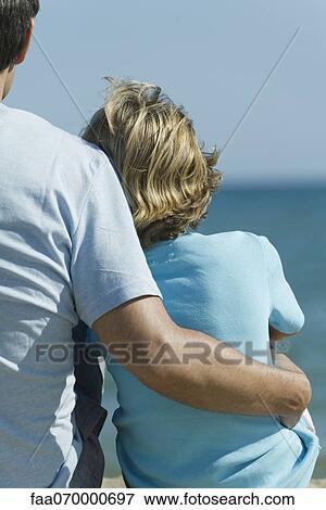 Father and son sitting together at the beach, rear view View Large Photo Image Stock Photo - Father and son sitting together at the beach, rear view. Fotosearch