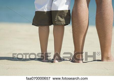 Father and son standing together on beach, cropped View Large Photo Image Stock Photo - Father and son standing together on beach, cropped. Fotosearch