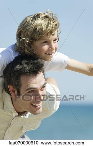 Stock Image - Father giving son piggback ride outdoors. Fotosearch