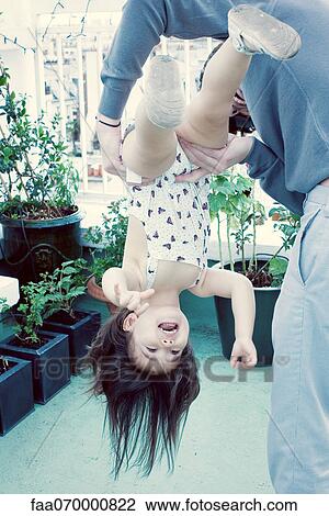 Stock Image - Father holding little girl upside down. Fotosearch