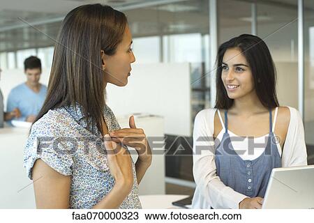 Female colleagues talking in office View Large Photo Image Stock Image - Female colleagues talking in office. Fotosearch