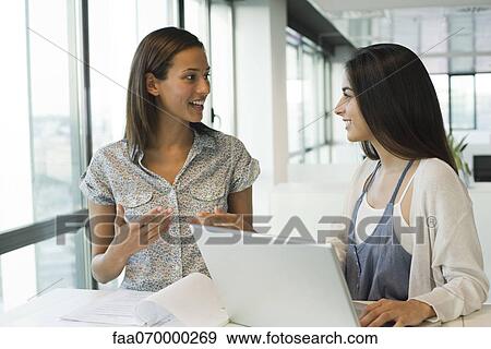 Stock Photo - Female colleagues working together in office. Fotosearch