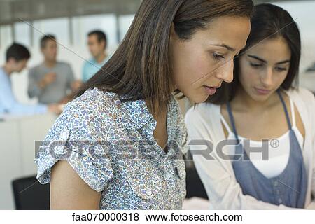 Female colleagues working together in office View Large Photo Image Stock Photo - Female colleagues working together in office. Fotosearch