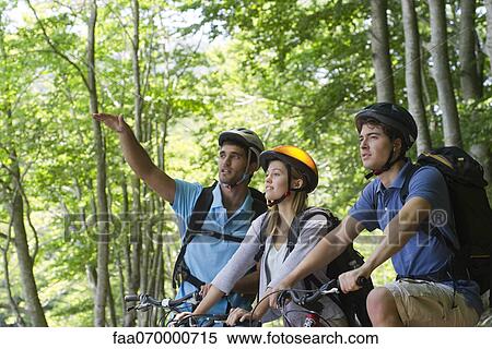 Friends bike riding in woods, man gesturing into distance View Large Photo Image Stock Photography - Friends bike riding in woods, man gesturing into distance. Fotosearch