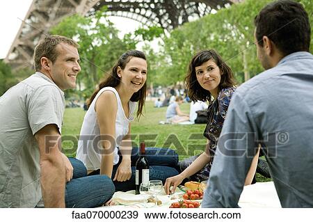 Stock Photo - Friends enjoying picnic at base of Eiffel Tower, Paris, France. Fotosearch