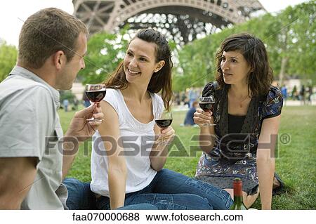 Stock Photo - Friends enjoying wine at picnic near Eiffel Tower, Paris, France. Fotosearch