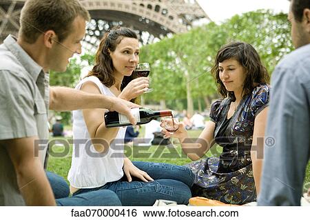 Friends enjoying wine at picnic near Eiffel Tower, Paris, France View Large Photo Image Stock Photograph - Friends enjoying wine at picnic near Eiffel Tower, Paris, France. Fotosearch