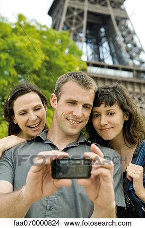 Picture - Friends posing for picture in front of Eiffel Tower, Paris, France. Fotosearch