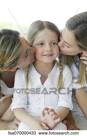 Stock Image - Girl being kissed on cheek by mother and grandmother. Fotosearch