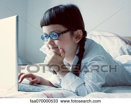 Girl lying on bed using laptop computer View Large Photo Image Stock Image - Girl lying on bed using laptop computer. Fotosearch