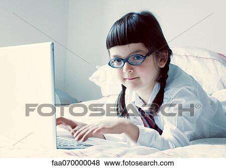 Stock Photo - Girl lying on bed using laptop computer. Fotosearch