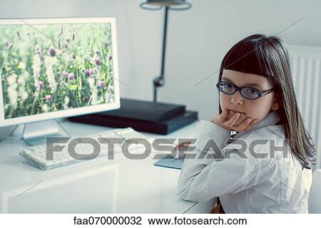 Stock Image - Girl sitting in front of desktop computer. Fotosearch