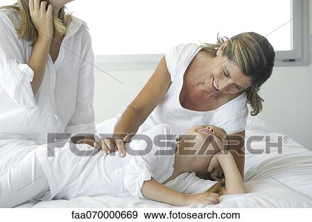 Stock Photo - Grandmother and granddaughter relaxing on bed. Fotosearch