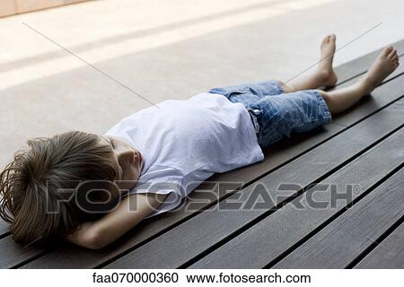 Stock Image - Little boy lying on back on deck. Fotosearch