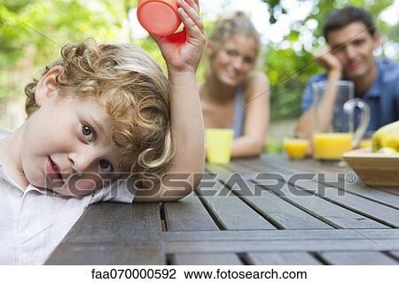 Little boy relaxing at picnic table with parents View Large Photo Image Stock Image - Little boy relaxing at picnic table with parents. Fotosearch