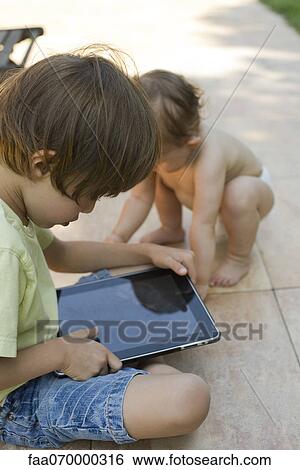 Little boy using digital tablet View Large Photo Image Stock Photograph - Little boy using digital tablet. Fotosearch