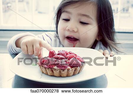 Stock Photo - Little girl getting taste of raspberry tart. Fotosearch