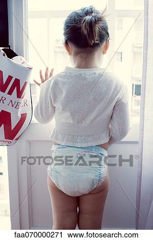 Stock Image - Little girl looking out of window, rear view. Fotosearch