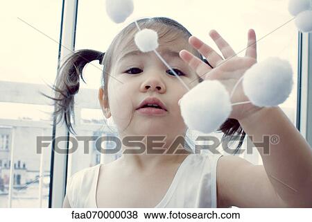 Little girl playing with hanging decoration View Large Photo Image Stock Photo - Little girl playing with hanging decoration. Fotosearch