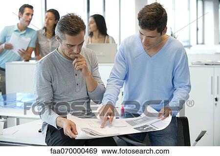 Male colleagues looking at blueprint together View Large Photo Image Stock Photo - Male colleagues looking at blueprint together. Fotosearch